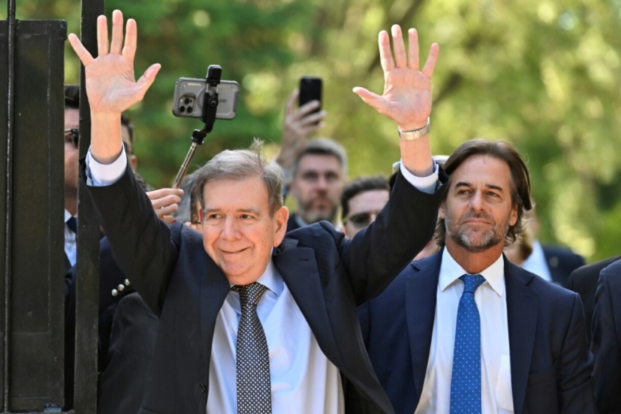 Venezuelan opposition leader Edmundo Gonzalez Urrutia (L) waves to supporters next to Uruguay's President Luis Lacalle Pou in Montevideo