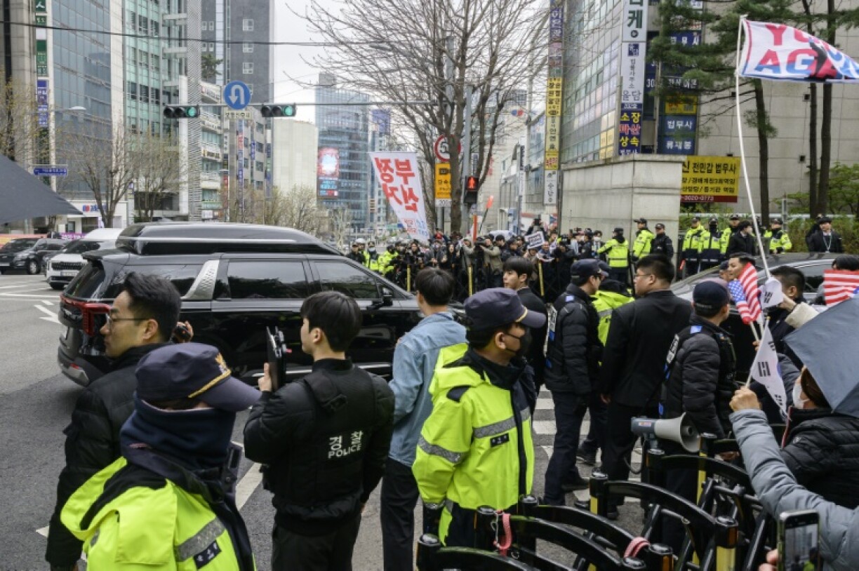 Supporters gather as police stand guard for the arrival of former president Yoon Suk Yeol's car (centre L) outside the Central District Court in Seoul