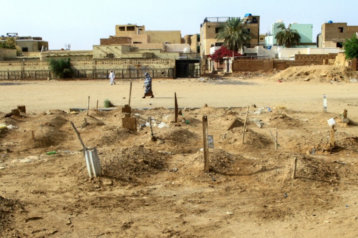 A Sudanese woman in Khartoum's twin-city Omdurman walks past graves -- during Sudan's war families have had to bury relatives wherever they can