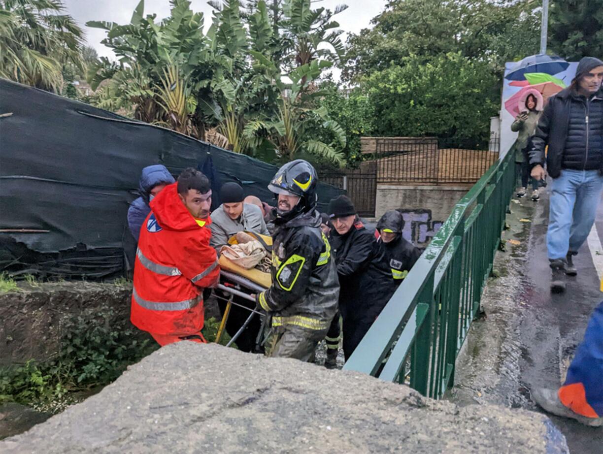 Italian firefighters carry a man out of his house on November 26, 2022 in Casamicciola in the southern Ischia island, following heavy rains that sparked a landslide.