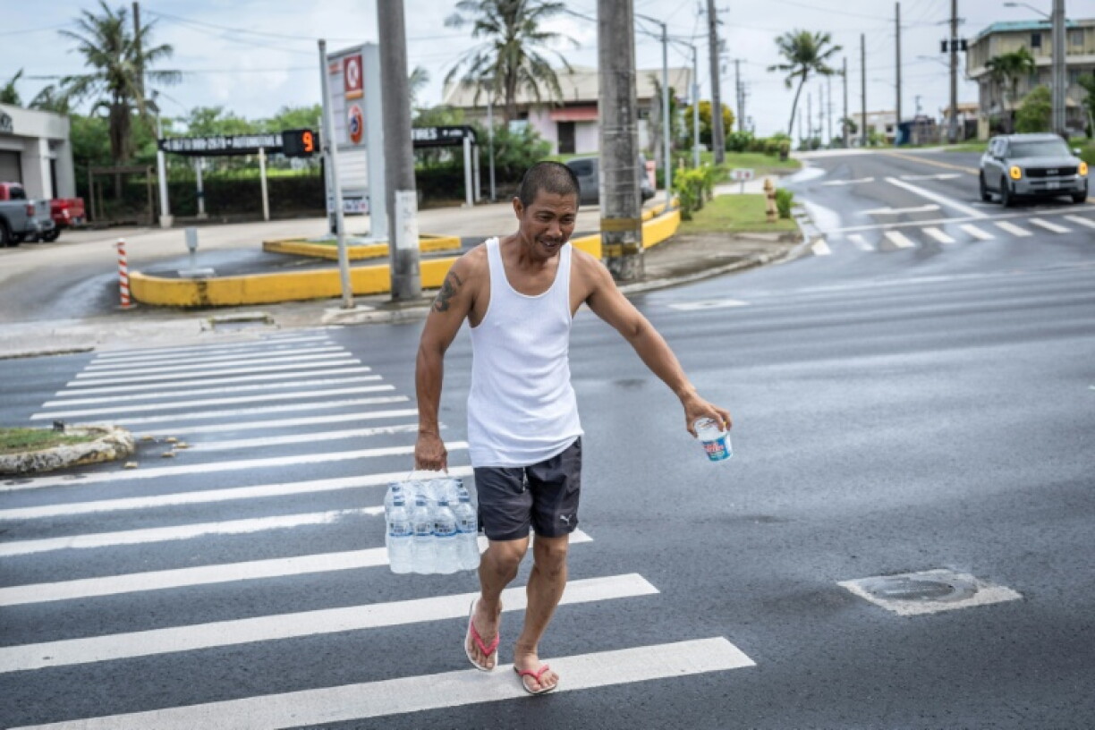 Un homme porte un pack de bouteilles d'eau à Guam alors que le typhon Bavi approche de l'île américaine du Pacifique le 5 juillet 2026