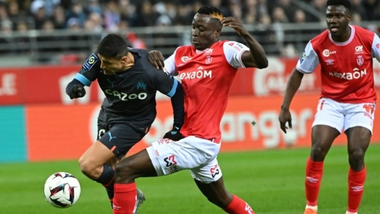 Alexis Sanchez, auteur d'un doublé pour l'OM à Reims en Ligue 1, déborde Folarin Balogun le 19 mars 2023 au stade Auguste-Delaune à Reims