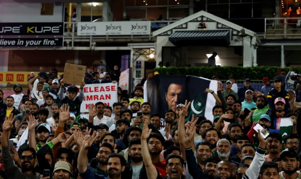 Pakistan supporters hold a poster of former Prime Minister and cricketer Imran Khan as they celebrate their team's victory