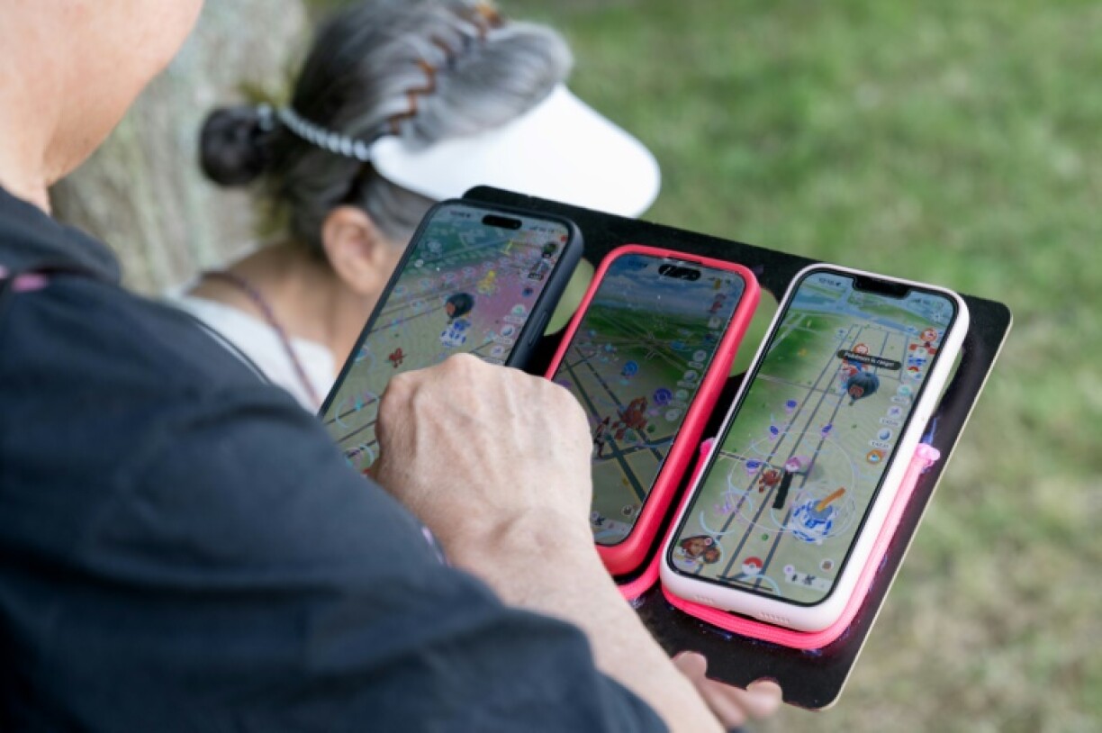 Un fan joue à Pokémon Go sur trois smartphones, le jour de l'ouverture du Pokémon Go Fest 2025, au Parc de Sceaux, au sud de Paris, le 13 juin 2025