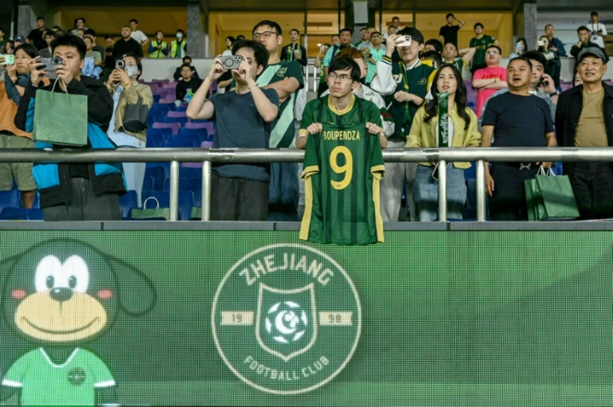 A Zhejiang FC fan holds up a shirt of Aaron Boupendza, the Gabon international footballer who was found dead earlier on Wednesday after an apparent fall from the 11th floor of a building