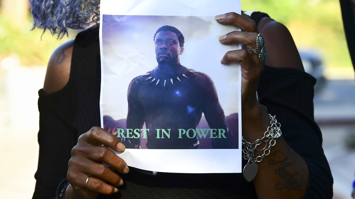 A woman holds a photograph of the late US actor and producer Chadwick Boseman during a candlelight vigil held by fans in Los Angeles on August 29, 2020.