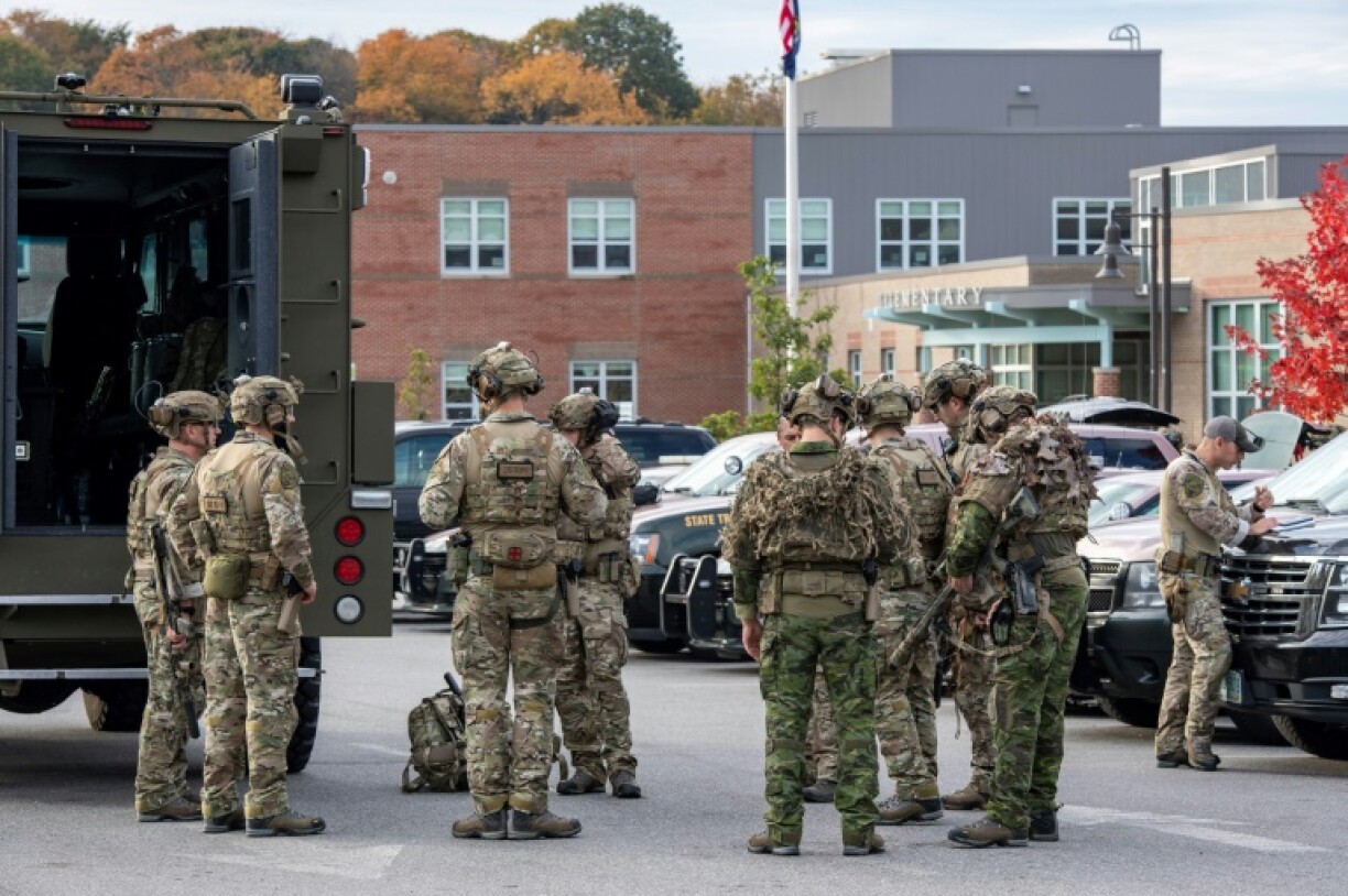Law enforcement officers gather outside Lewiston High School, Maine in a massive manhunt for a gunman who killed 18