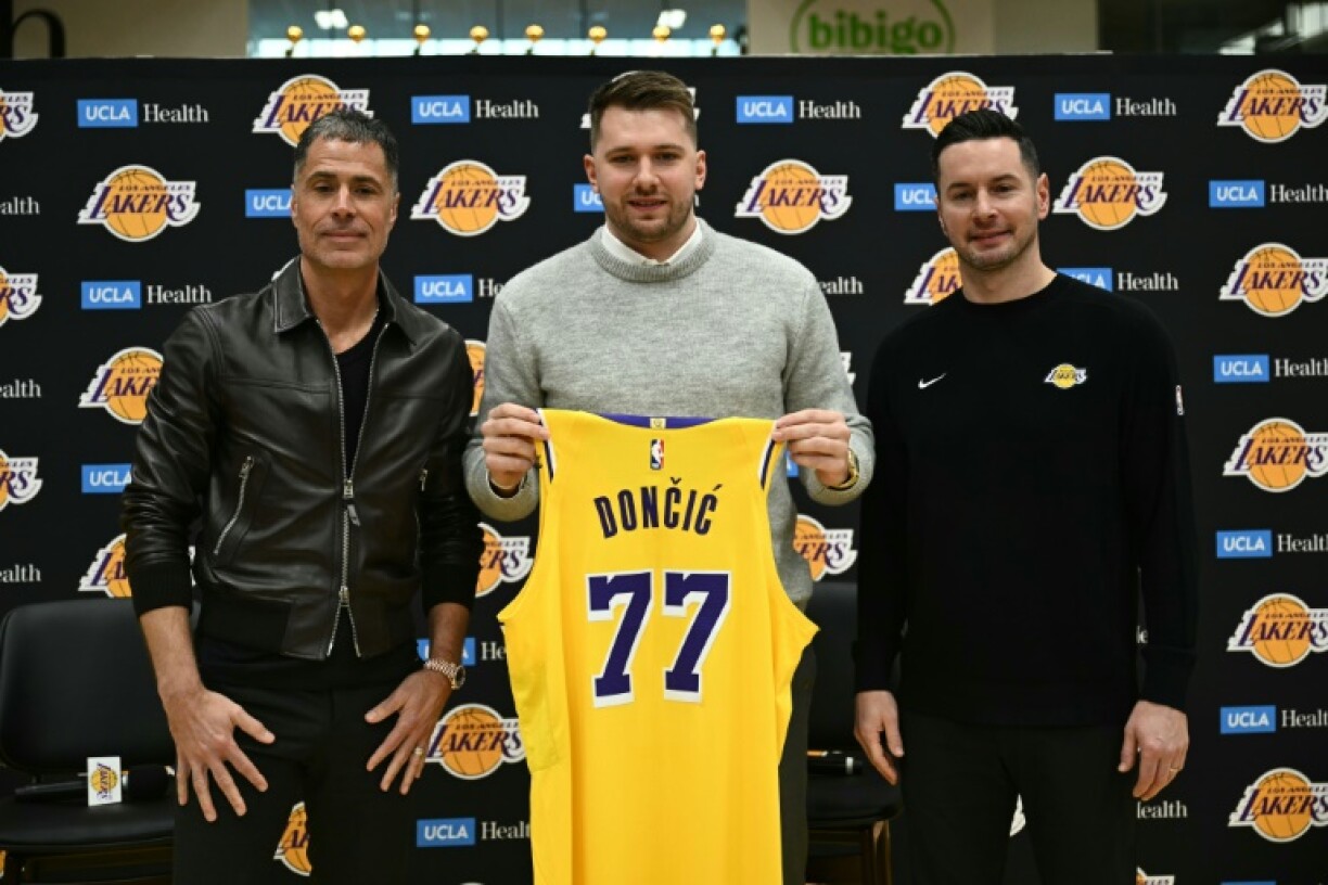 Luka Doncic (center) alongside Los Angeles Lakers general manager Rob Pelinka (left) and head coach JJ Redick (right)