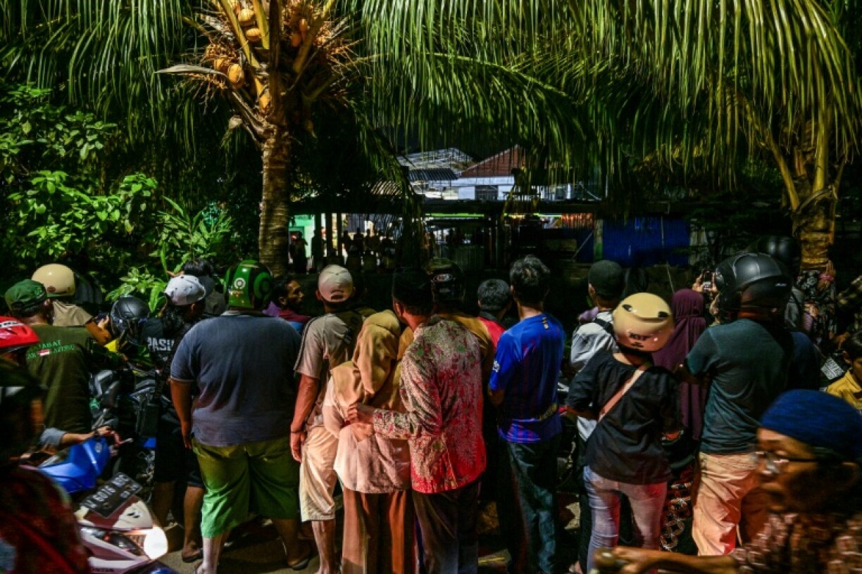 People gather to watch as a rescue operation is underway at the site of a collapsed building on Indonesia's Java island