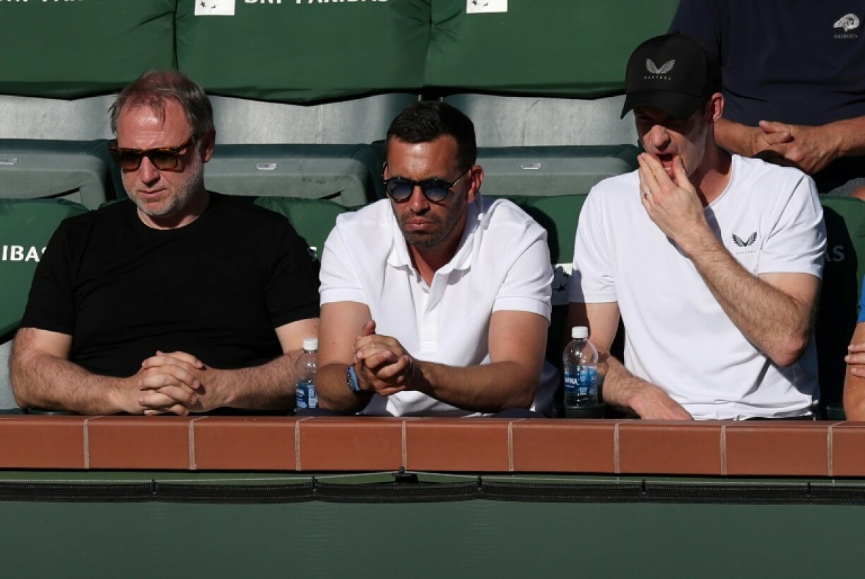 Andy Murray (black cap) coach of Novak Djokovic of Serbia watches as Djokovic falls to Botic van de Zandschulp in the second round at Indian Wells
