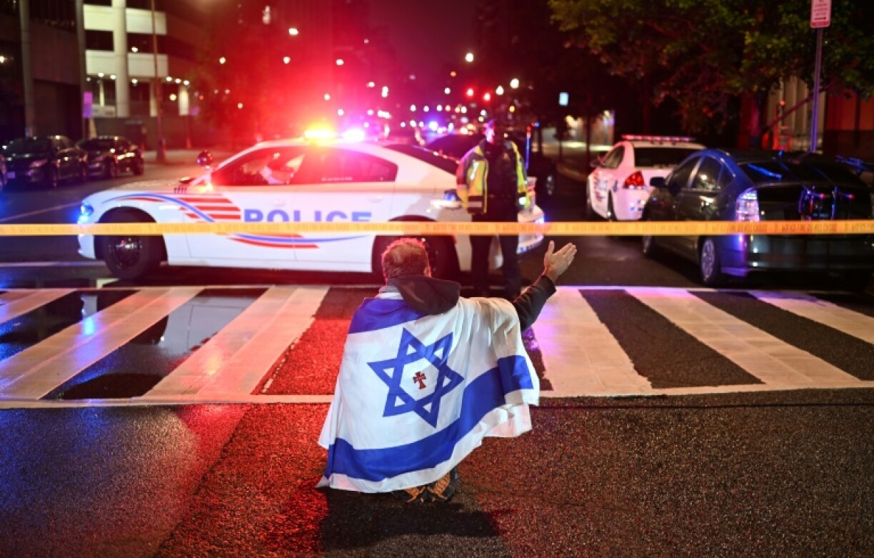 A man draped in the Israeli flag, bearing a cross and the name