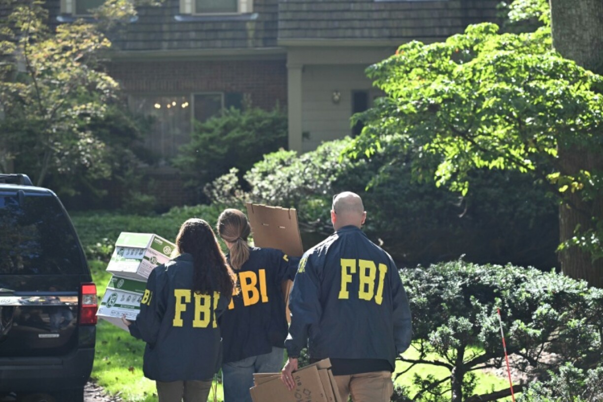 FBI agents carry boxes as they arrive at the house of John Bolton, President Donald Trump's former national security adviser