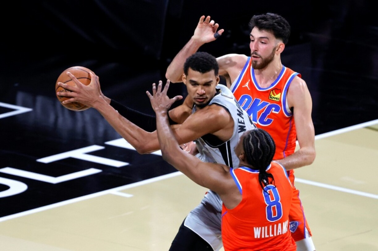 Victor Wembanyama (c) est entouré de Jalen Williams (de dos) et Chet Holmgren lors du match NBA des San Antonio Spurs contre l'Oklahoma City Thunder, le 13 décembre 2025 à Las Vegas