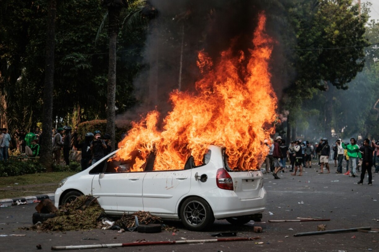 A car burns after being set ablaze during a protest in Jakarta