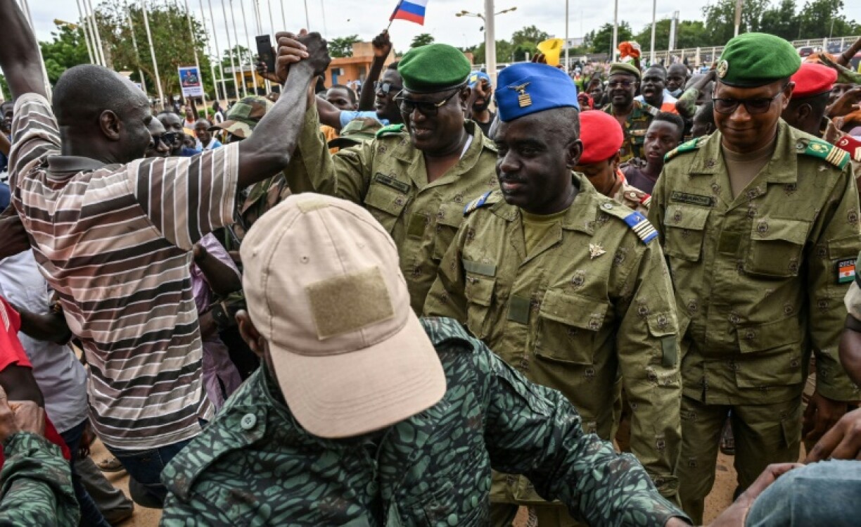 Des manifestants saluent les militaires du Conseil national pour la sauvegarde de la patrie (CNSP), qui ont pris le pouvoir au Niger (de gauche à droite: le général Mohamed Toumba, le colonel Amadou Abdramane et le colonel Ousmane Abarchi), le 6 août 2023 à Niamey
