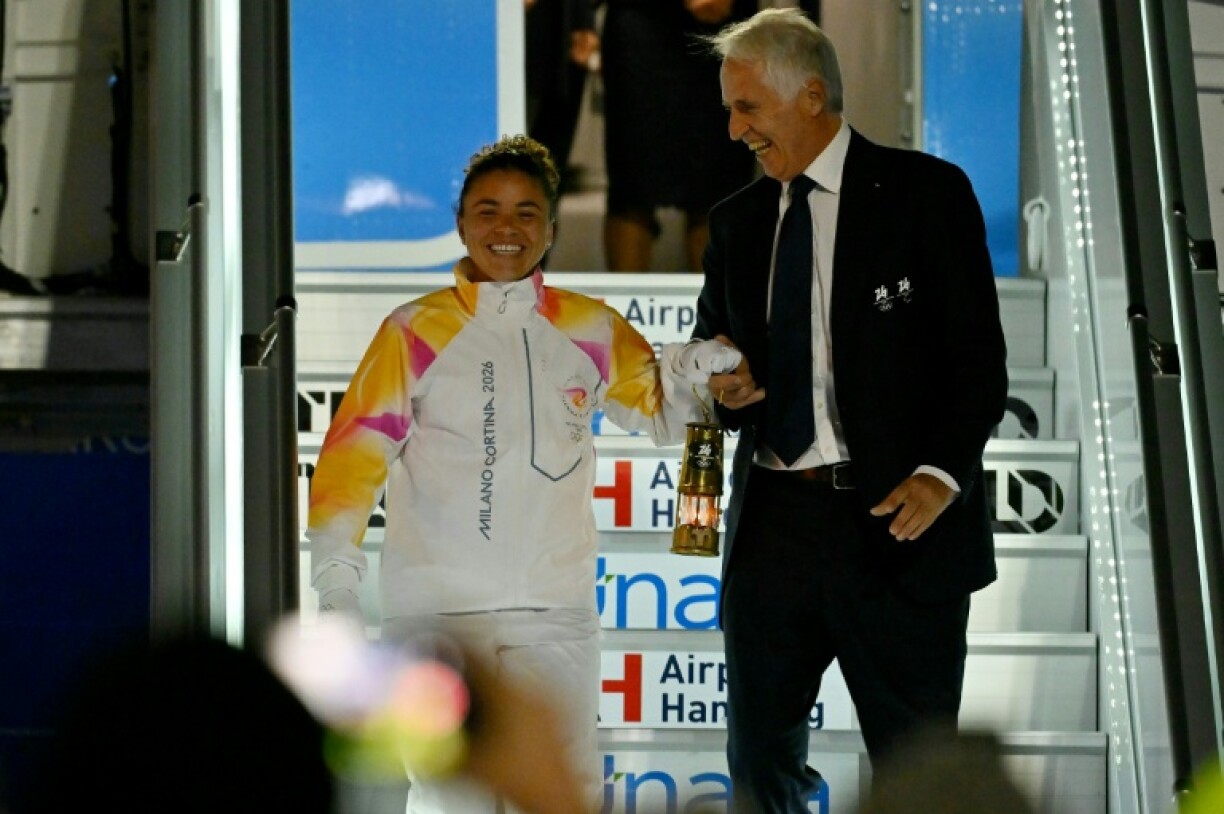 La joueuse de tennis Jasmine Paolini et le président du comité d'organisation des JO-2026 Giovanni Malago à leur arrivée avec la flamme olympique à l'aéroport de Fiumicino le 4 décembre 2025 à Rome