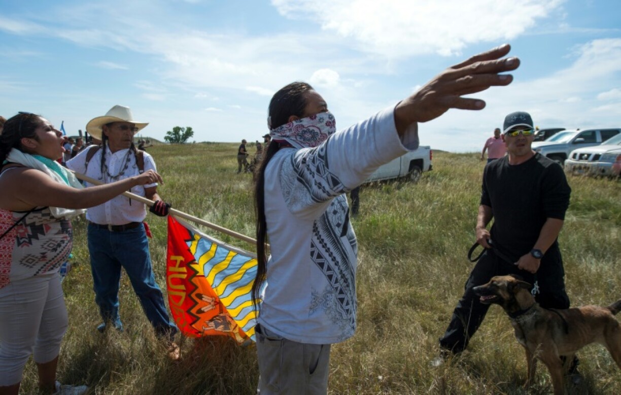 A protester holds up his arms in front of private security guards and guard dogs at a work site for the Dakota Access Pipeline near Cannon Ball, North Dakota in September 2016