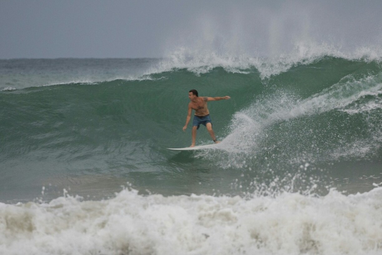 A surfer rides a wave at La Pared beach as Hurricane Erin approaches in Luquillo, Puerto Rico