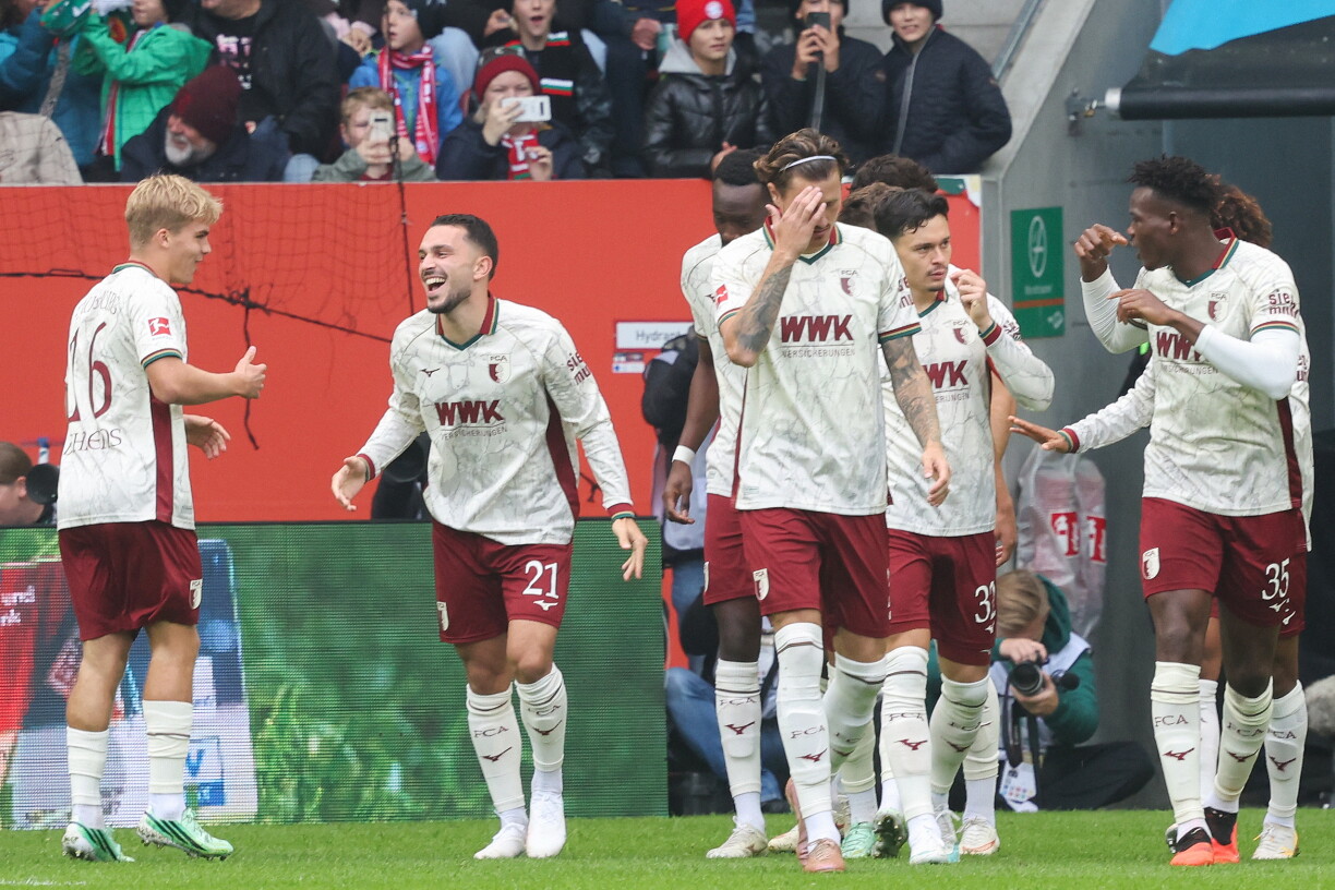 Augsburg's German midfielder #19 Robin Fellhauer (hidden) celebrates scoring the opening goal with his teammates during the German first division Bundesliga football match between FC Augsburg and FC Bayern Munich in Augsburg, southern Germany on October 10, 2026. (Photo by Karl-Josef HILDENBRAND / AFP) / DFL REGULATIONS PROHIBIT ANY USE OF PHOTOGRAPHS AS IMAGE SEQUENCES AND/OR QUASI-VIDEO