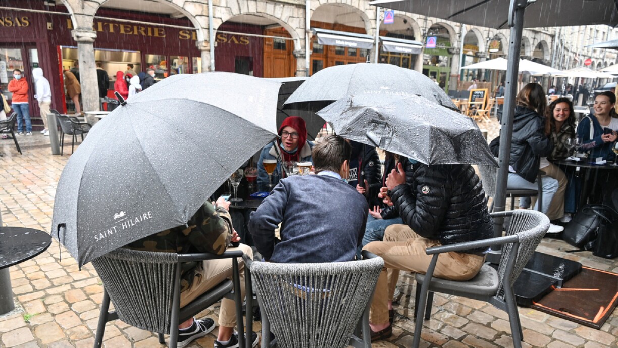 Customers hold their umbrellas as they sit on the terrace of a bar in Arras, northern France, on May 19, 2021 as cafes, restaurants and other businesses re-opened after closures during the coronavirus (Covid-19) pandemic.